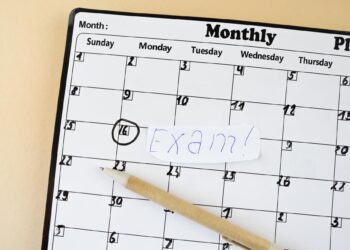 Üzerinde 'Exam!' yazılı kağıt bulunan masa takvimi ve tükenmez kalem.