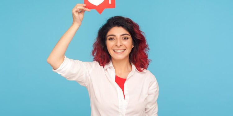 Beyaz gömlekli kadın elinde üzerinde kalp ikonu olan kırmızı bir bildirim tutuyor.