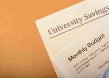 Üzerinde University Savings ve Monthly Budget yazan evraklar masada duruyor.