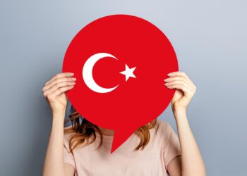 Yüzünün önünde kırmızı renkli Türk bayrağı şekilli konuşma balonu tutan kadın.