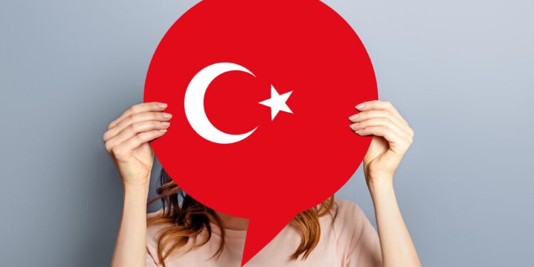 Yüzünün önünde kırmızı renkli Türk bayrağı şekilli konuşma balonu tutan kadın.