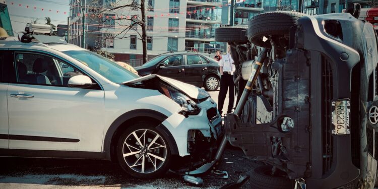 Şehir içinde kazada devrilmiş siyah bir otomobil ve arkasında beyaz araç.