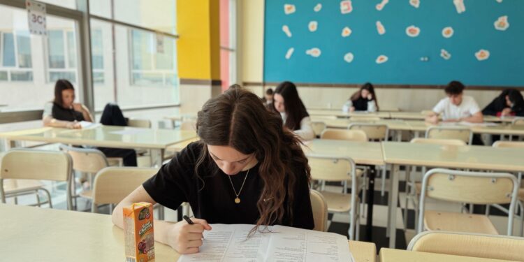 Sınıfta sırada oturan ve sınav kağıdına yazan genç kız öğrenci.