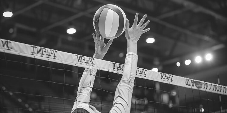 Salonda file önünde topa doğru ellerini uzatan voleybolcu.