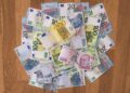 Ahşap zemin üzerine dağınık şekilde serpiştirilmiş Türk lirası ve euro banknotları.