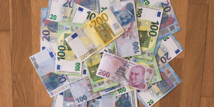 Ahşap zemin üzerine dağınık şekilde serpiştirilmiş Türk lirası ve euro banknotları.