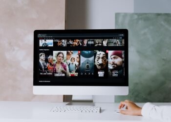 Bilgisayar ekranında Netflix dizi ve film arayüzü açık olan çalışma masası