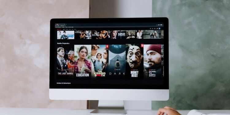 Bilgisayar ekranında Netflix dizi ve film arayüzü açık olan çalışma masası