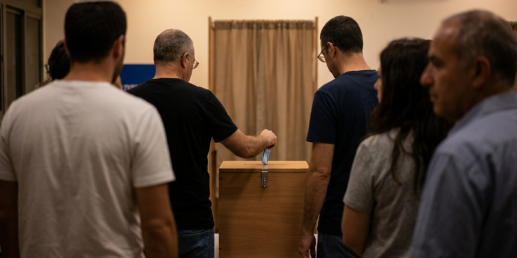 Kapalı bir alanda sandık başına giderek oy kullanan İsrailli seçmenler