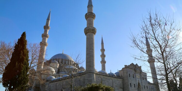 Açık mavi gökyüzü altında yükselen minareleri ve kubbesiyle tarihi cami