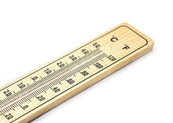 Ahşap bir zemine yerleştirilmiş Celsius ve Fahrenheit derecelerini gösteren bir termometre.