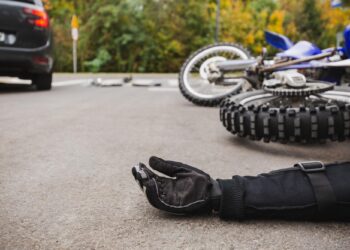 Yere düşmüş bir motosiklet ve motosiklet sürücüsünün eldivenli eli.
