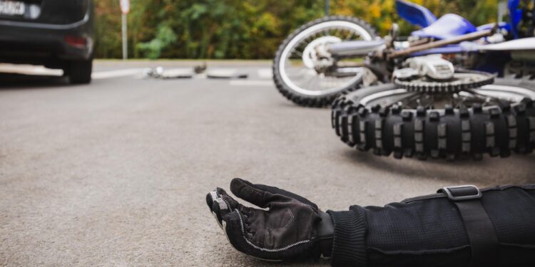Yere düşmüş bir motosiklet ve motosiklet sürücüsünün eldivenli eli.