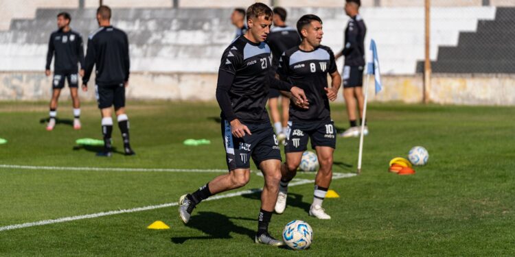 Saha kenarındaki yeşil çimlerde futbol antrenmanı yapan siyah formalı oyuncular
