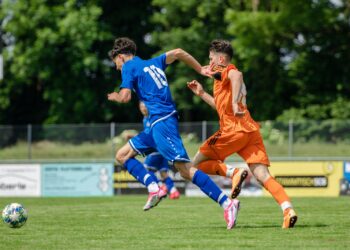 Futbol sahasında iki genç futbolcunun top kapma mücadelesi anı