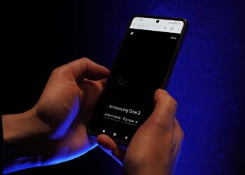 Karanlık bir ortamda ellerinde akıllı telefon tutan bir kişinin yakın plan görüntüsü.