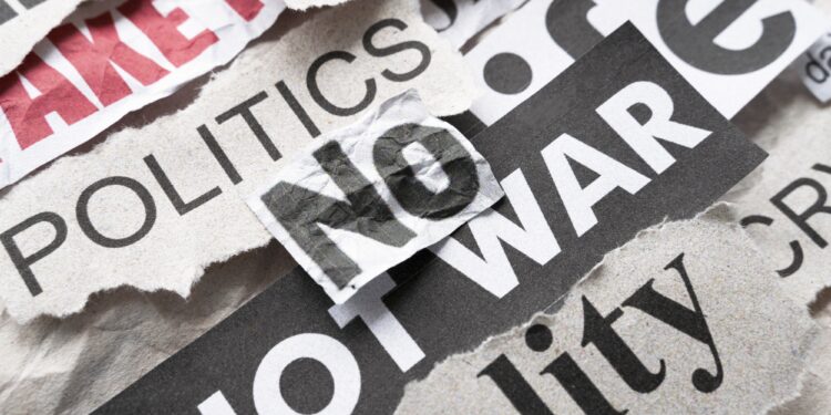 Üzerinde 'No War' ve 'Politics' yazan kırpılmış gazete kupürleri ve küpür yığınları.