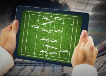 Tablet ekranında futbol taktiği ve oyun şeması gösteren eller.